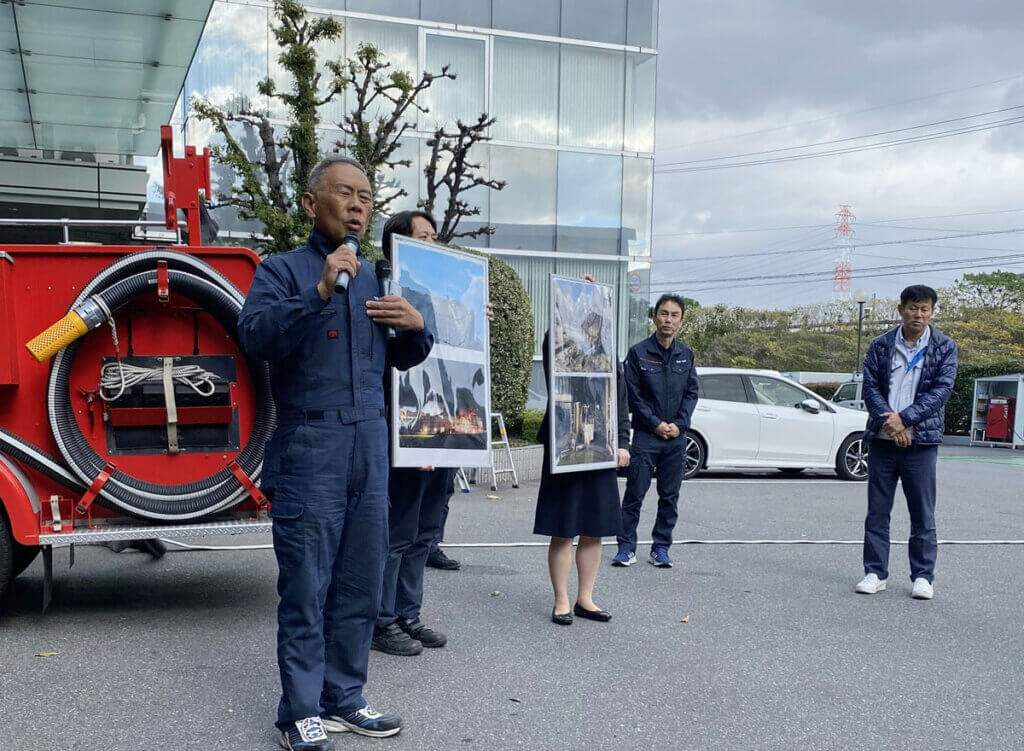 海部南部消防組合の消防車両の前で、訓練内容の説明を受ける中部第一グループの社員たち