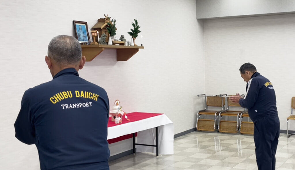 中部第一輸送の仕事始め式の準備風景。CHUBU DAIICHIのロゴ入り作業着を着た社員が神棚に祈りを捧げる