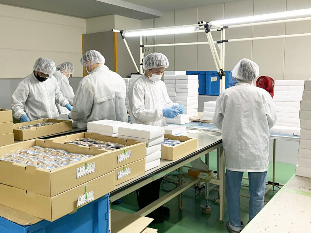 中部第一輸送 流通部加工部門の作業風景。スタッフが制服・帽子を着用し、丁寧に作業を行っている様子。